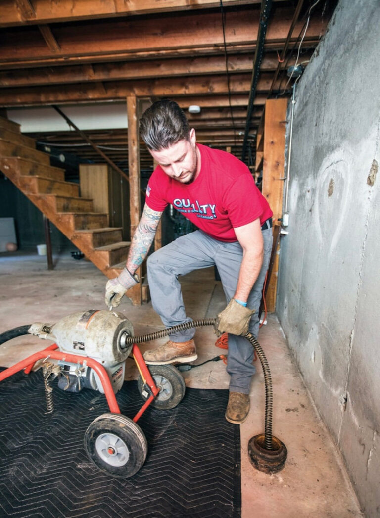 Ironside plumber running a drain cleaning machine in a basement